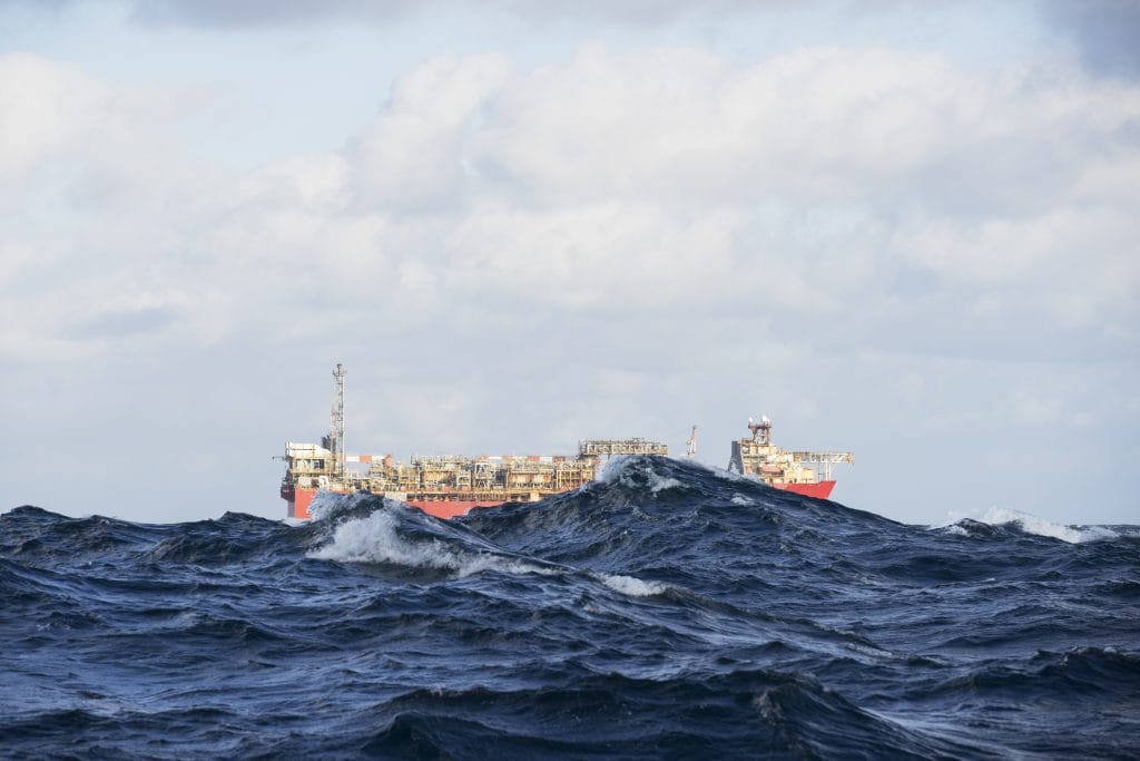 An FPSO floats on the horizon partially obscured by waves during rough weather