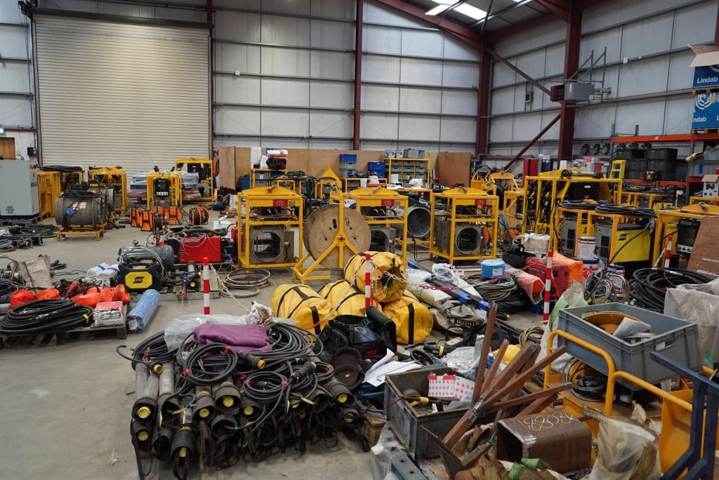 A busy workshop has equipment laid out across the workshop floor ready to be loaded into containers.