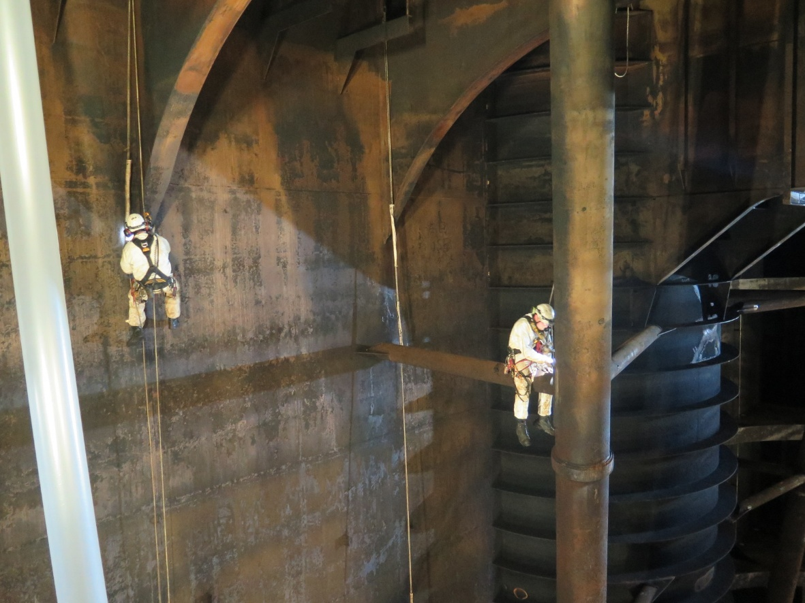 FPSO Inspectors conducting inspection and repairs suspended from ropes, with the tank lit by ATEX LED lights