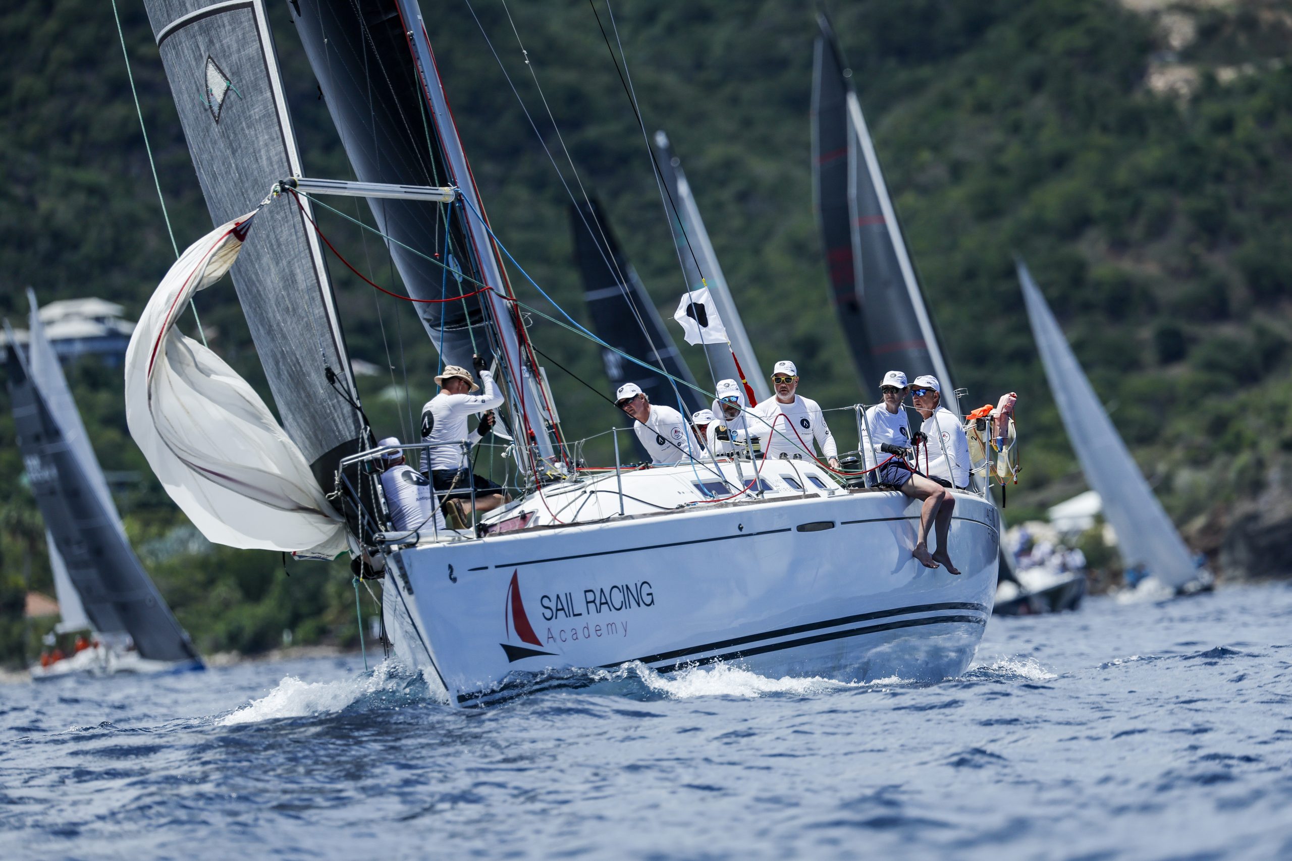 Professional sailors and six-man crew in bright sunshine