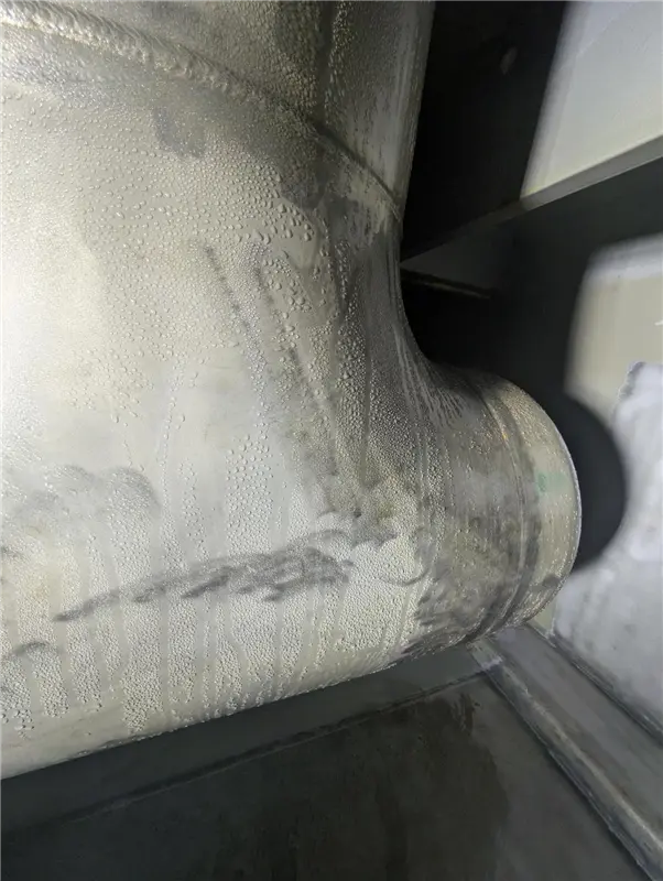 Condensation forming on in-service pipework inside a freshwater tank, with moisture draining onto tank surfaces and creating challenging atmospheric conditions during coating refurbishment works.